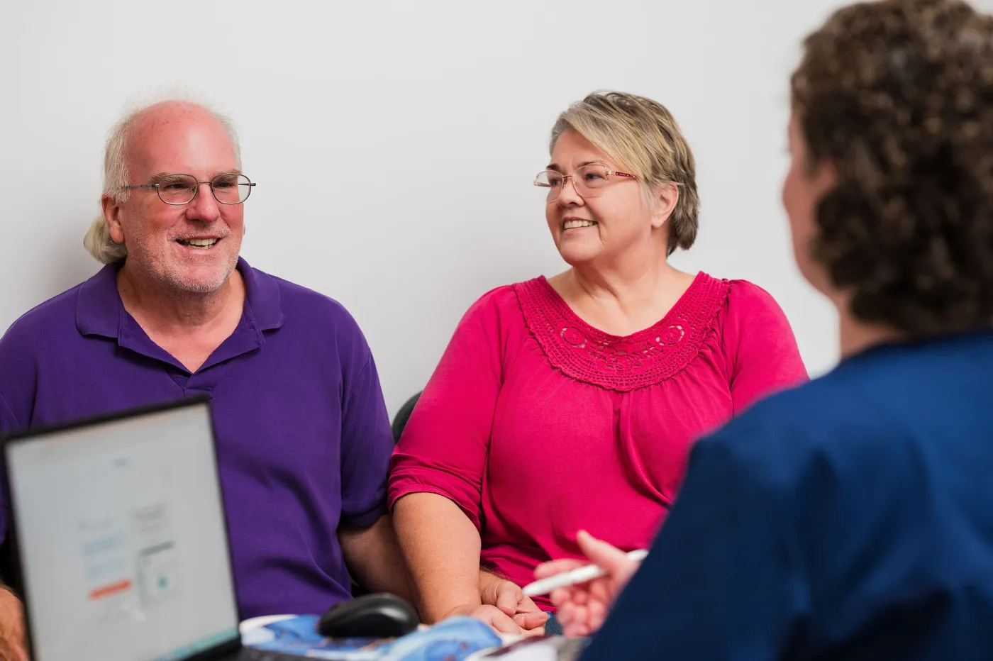 A smiling couple talking with Dr. Foster during a visit